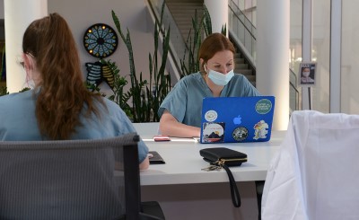 Back of one medical student, another facing forward at computer