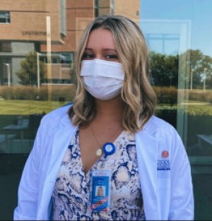 Heying wearing mask and white coat outside HEB