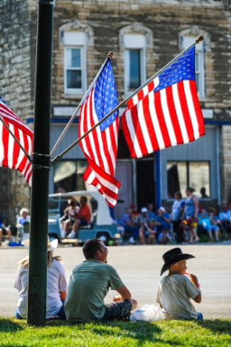 Three American flags near children watching a parade