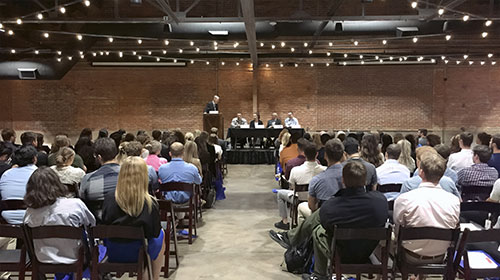 audience seated in front of a stage with Dr. Garold Minns speaking at a podium